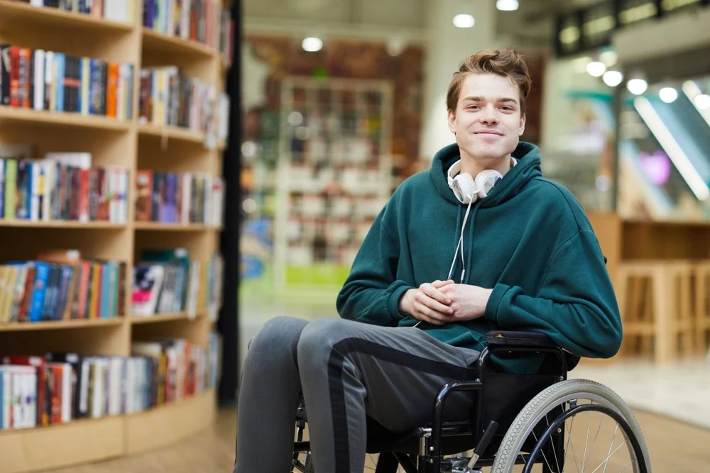 Young man on wheelchair in a library