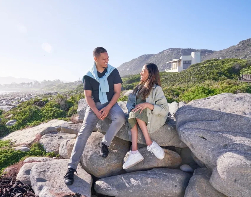 disabled woman with caretaker sitting on rocks by the beach