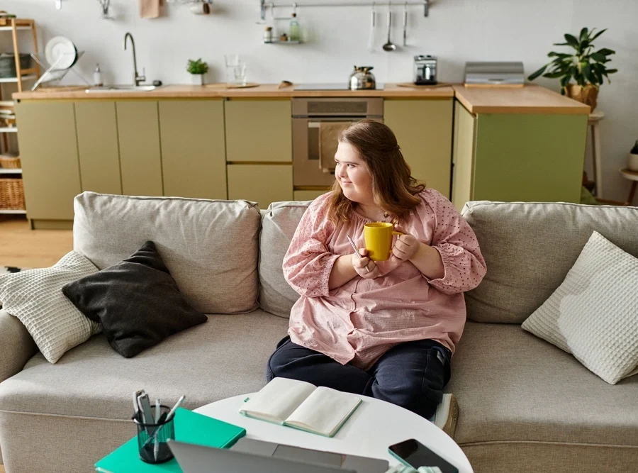 woman with down syndrome disability sitting on sofa in her home