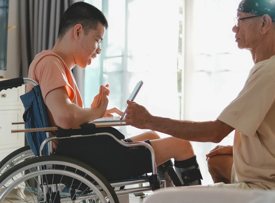 caretaker with young down syndrome boy and looking at phone
